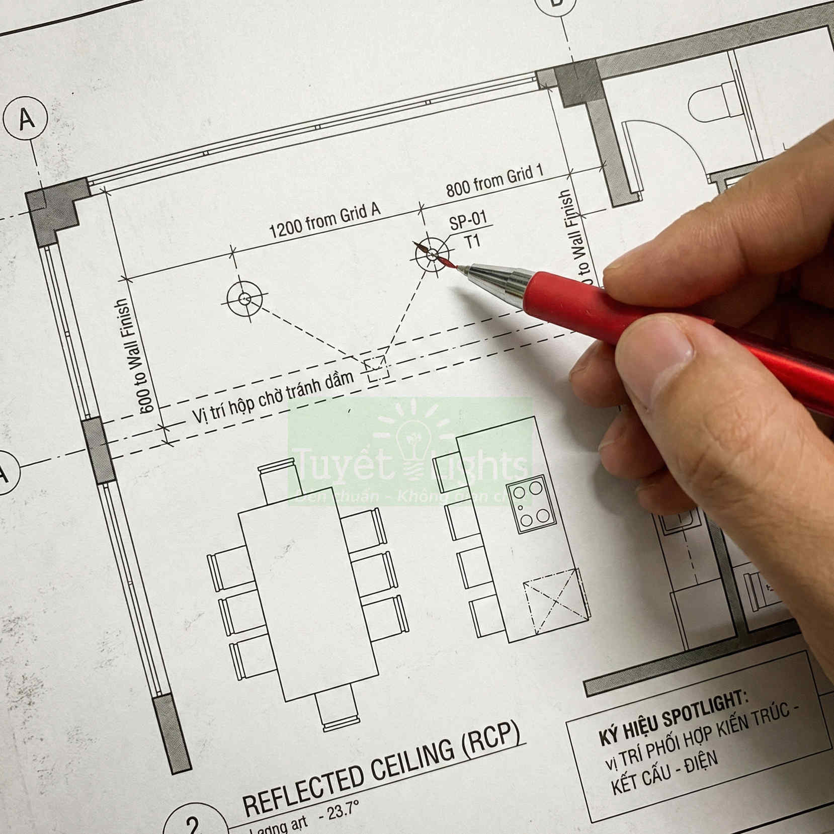 Bản vẽ thiết kế chiếu sáng nội thất với tay cầm bút đỏ chỉ vào vị trí lắp đèn spotlight