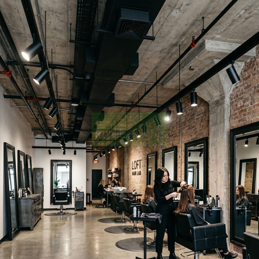 Nhân viên salon tóc đang cắt tóc cho khách trong không gian salon hiện đại, ghế da đen và gương lớn