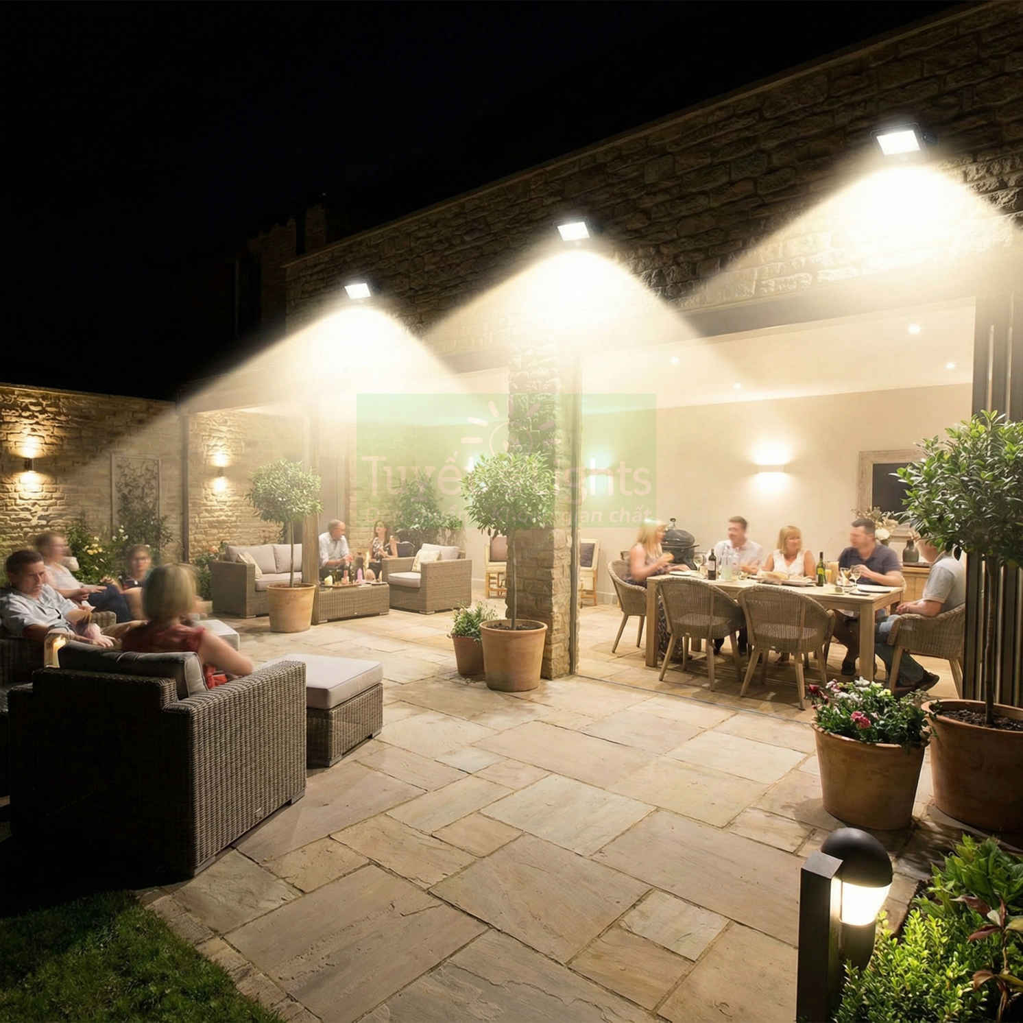 Đèn pha LED chiếu sáng sân vườn ngoài trời với bàn ghế mây nhựa và chậu cây trang trí