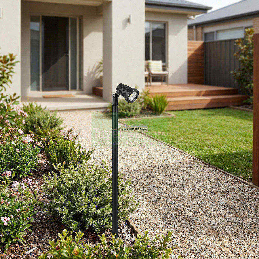 Đèn chiếu sáng sân vườn màu đen lắp trên lối đi cạnh bồn cây trước hiên nhà