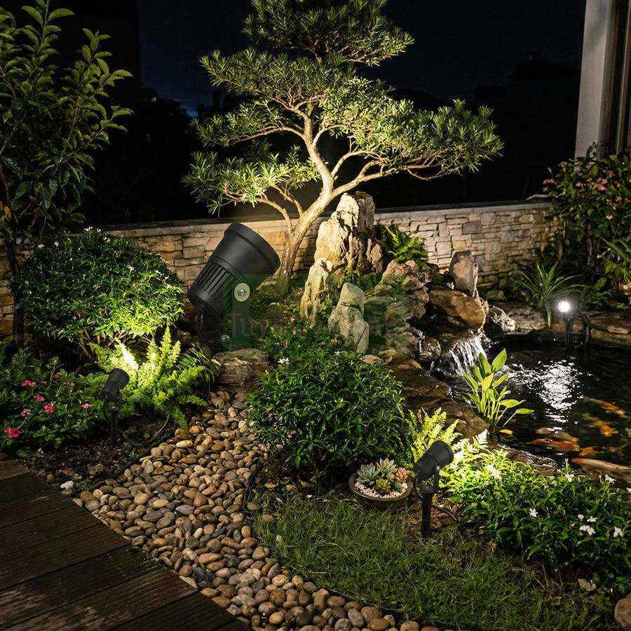 Đèn chiếu sáng sân vườn ngoài trời rọi cây và hồ cá ban đêm